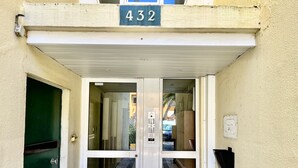 A building entrance with a double door, a small balcony with a number sign, and a security camera. - Guia Acacias Apartment (Cascais)