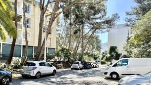 A street lined with parked cars and trees, with a building in the background. - Guia Acacias Apartment (Cascais)