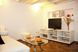 A modern living room with a white sofa, a glass coffee table, a flat-screen TV on a white entertainment unit, and a vase with flowers. - Best Loft In The Heart Of Recoleta. Stunning Designed. Unbeatable Location. (Ciudad Autonoma de Buenos Aires)
