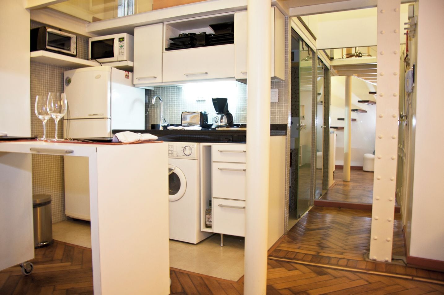 A compact kitchen with a microwave, oven, and washing machine.