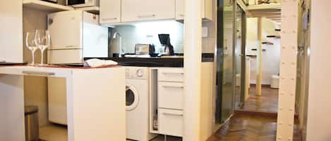 A compact kitchen with a microwave, oven, and washing machine.
