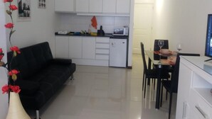 Un espace de vie compact comprenant une kitchenette, un coin repas et un canapé noir.