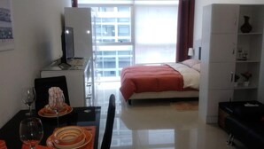 Une chambre d’hôtel comprenant un lit, un bureau avec une chaise, une télévision et un coin repas avec une table et des chaises.