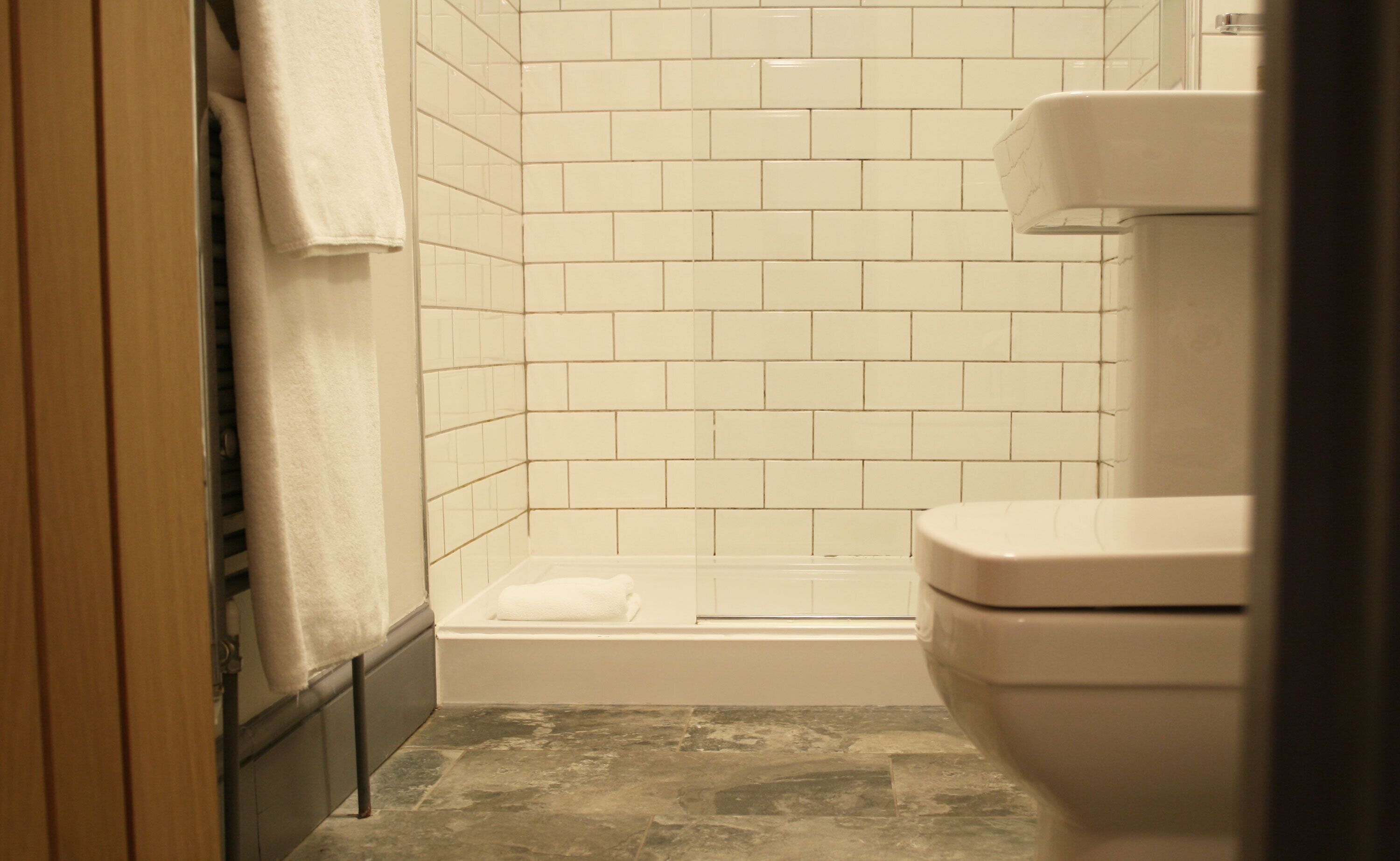 Un baño con paredes de azulejos blancos, una bañera y un inodoro.