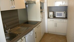 A compact kitchen with a sink, dishwasher, microwave, and a coffee maker on the countertop. - Apartment 2 Rooms + Terrace 10 m² -Front de Mer, Face Plage de Sable  (Bandol)