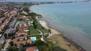An aerial view of a coastal residential area with houses, a beach, and a marina. - Lakefront apartment with pool and WiFi (Sirmione)