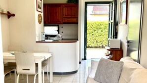 A modern living room with a white sofa and a dining area with a white table and chairs. - Lakefront apartment with pool and WiFi (Sirmione)