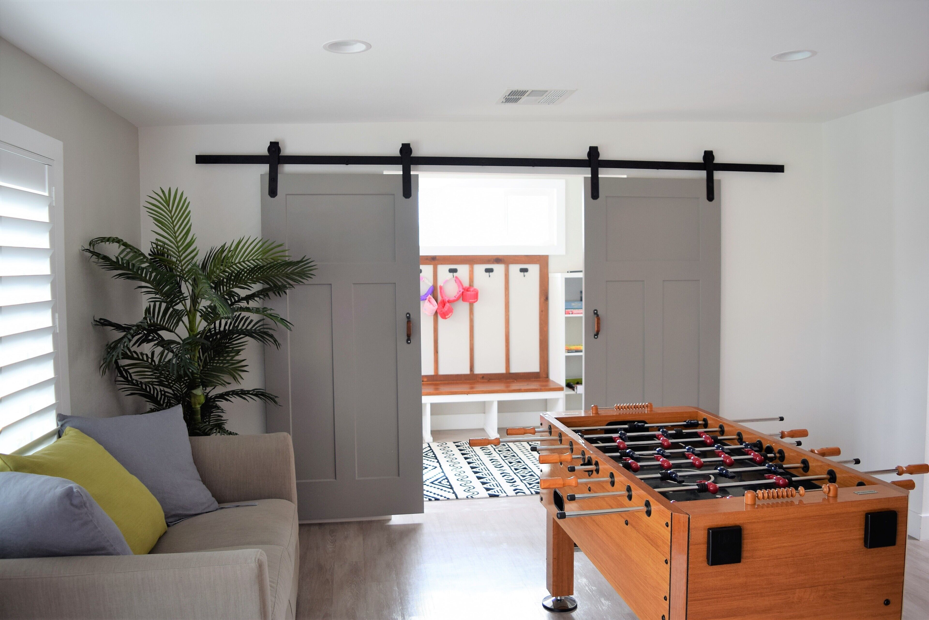 Een kamer met een bank, een tafelvoetbaltafel en een plant.
