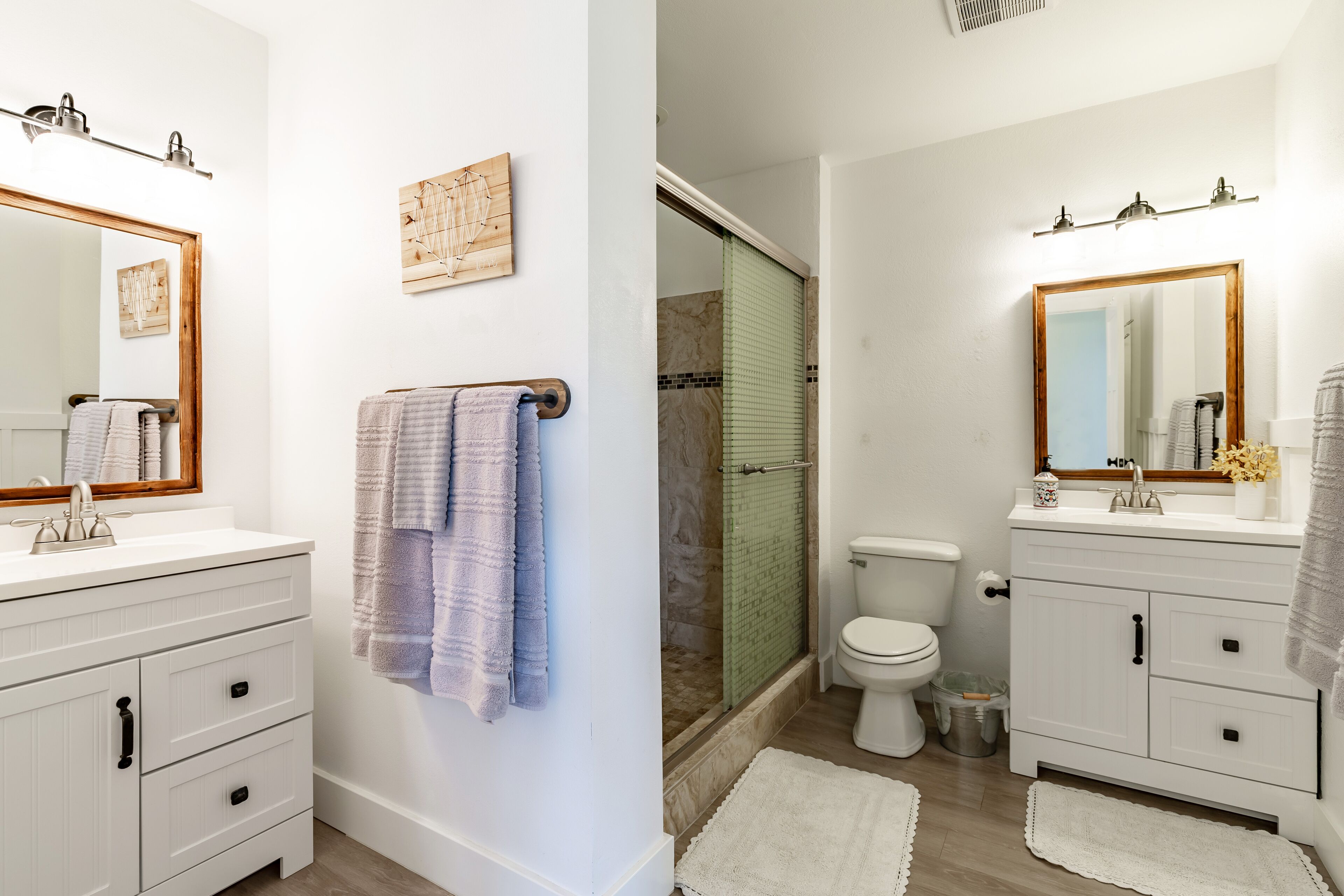 A modern bathroom with a white vanity, a large mirror, a shower with a glass door, and a toilet.