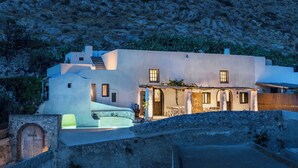 A modern house with a stone facade, a small patio with outdoor furniture, and a view of a rocky hillside. - Canava Villas #2 with Private Pool @Medieval Village , Santorini (Santorini)