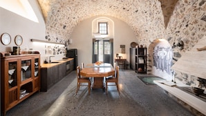 A rustic kitchen with a stone ceiling, wooden cabinets, and a round dining table. - Canava Villas #2 with Private Pool @Medieval Village , Santorini (Santorini)