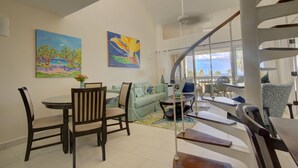 Un'ampia zona giorno con tavolo e sedie da pranzo, divano e una scala.
