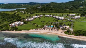 Vista aerea di un resort con diversi edifici, una spiaggia e una zona piscina.