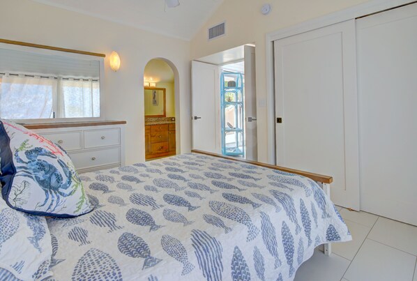 A bedroom with a bed, a dresser, a mirror, and a door leading to another room. - Oceanfront, 100% -5 Stars, GentleWinds.Com, 3 Bed,3 Bath Premier Host (Christiansted)