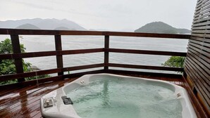 Un jacuzzi en una terraza de madera con vista al mar y las montañas.
