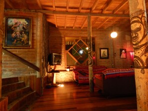 A cozy room with a wooden ceiling, a fireplace, a television, and a bed with patterned bedding. - Dogs and Fish Dream Land (Baños de Agua Santa)