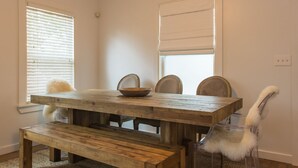 Un comedor con mesa de madera, cuatro sillas y un banco.