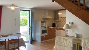 Un espacio habitable compacto con cocina, comedor y una escalera.