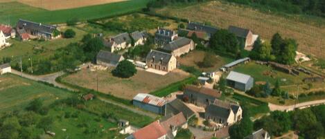An aerial view of a rural village with houses, fields, and a small road.
