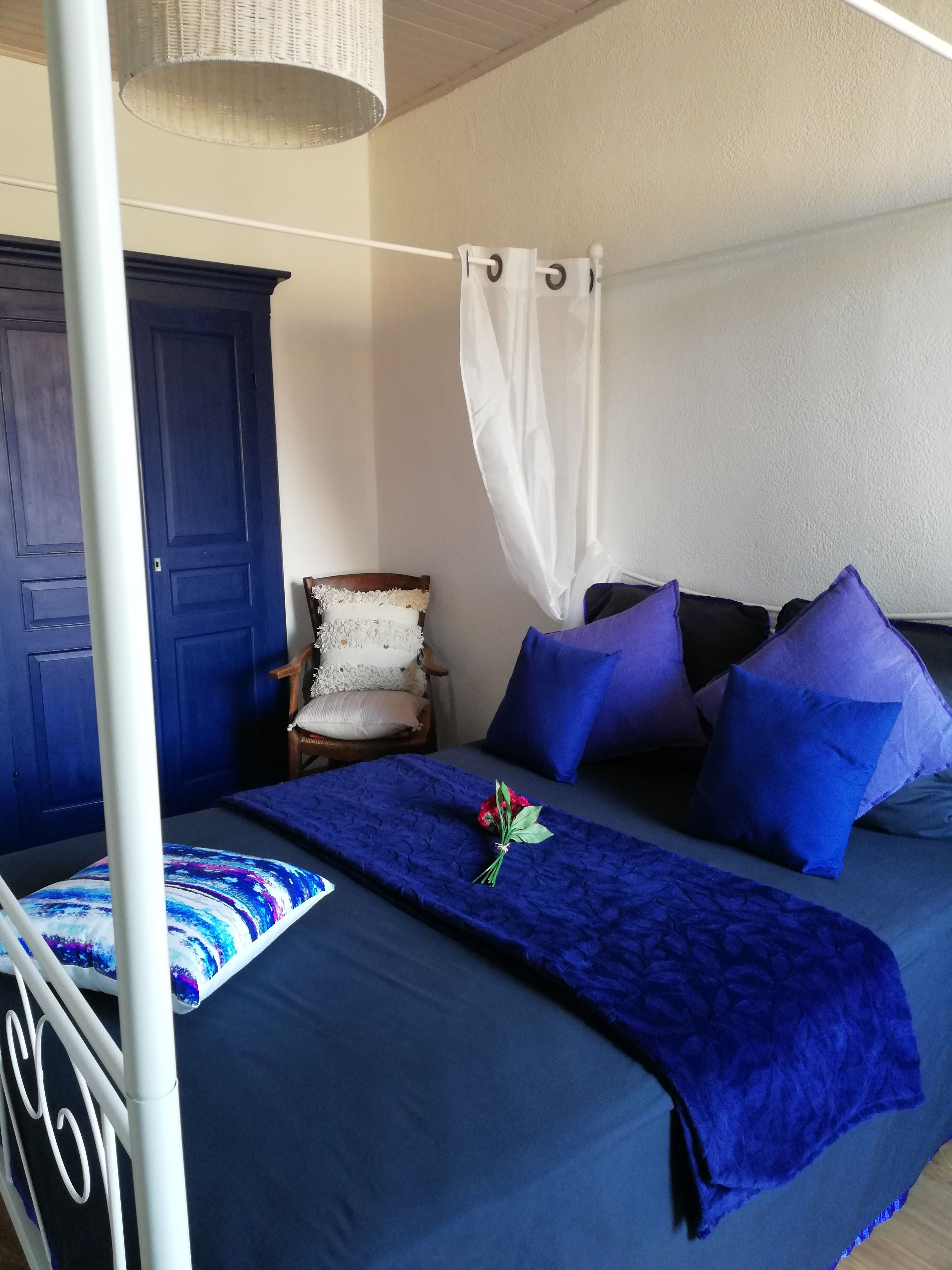 A bedroom with a bed, a chair, a wardrobe, and a canopy.