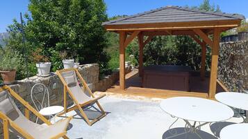 A wooden gazebo with a tiled roof, surrounded by stone walls and potted plants.