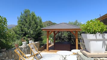 A patio with a wooden pergola, stone seating, and potted plants.