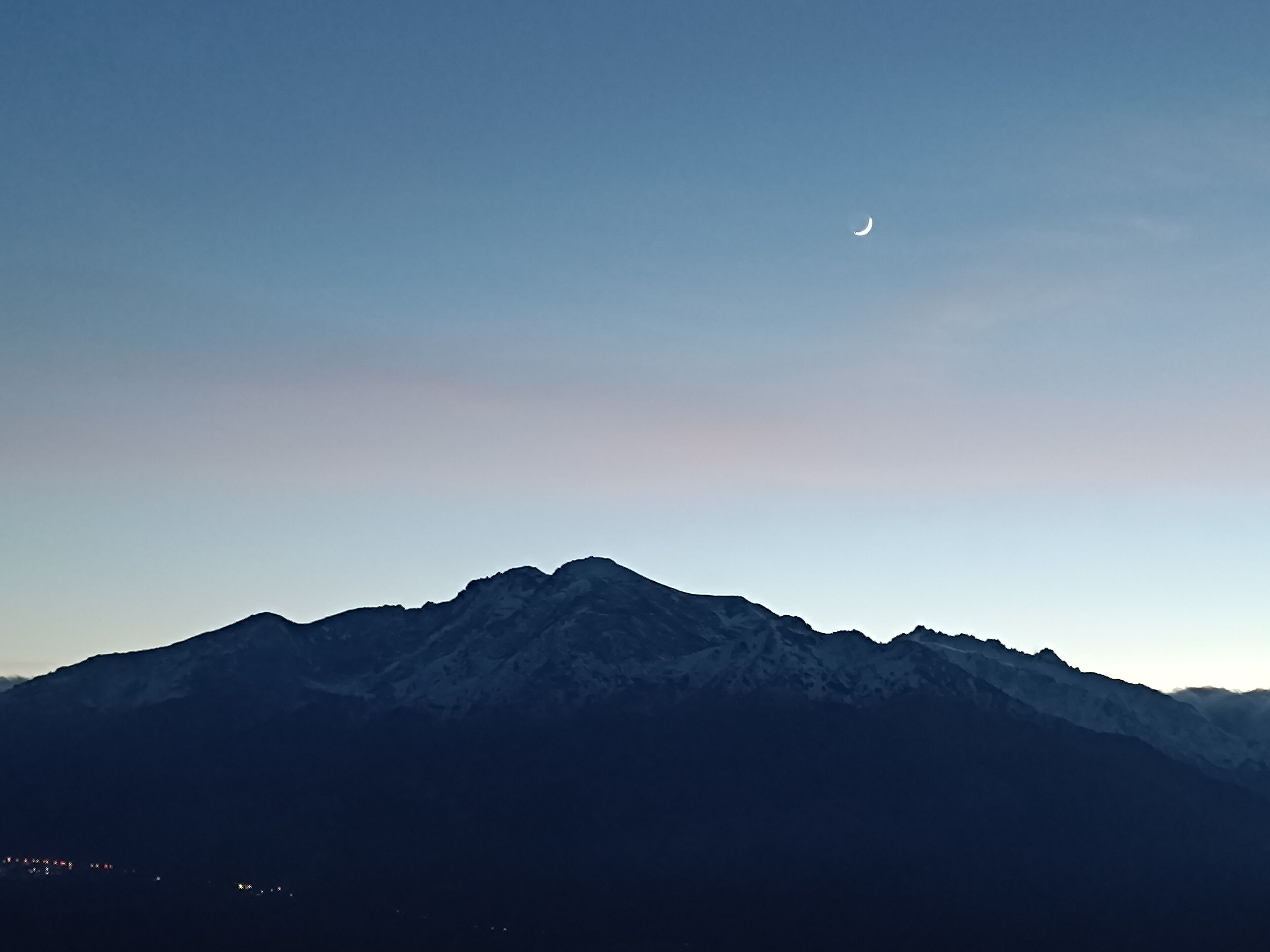 A mountain range with a crescent moon in the sky.