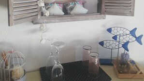 Une chambre à coucher avec un grand miroir, un lit agrémenté d’oreillers blancs et à motifs, une table de chevet ornée d’objets décoratifs et une fenêtre avec un rideau.