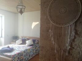 Un dormitorio con cama, un adorno en la pared y una lámpara colgante.