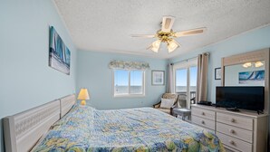 Une chambre à coucher avec un lit, un ventilateur de plafond, une télévision et une fenêtre donnant sur un beau paysage.
