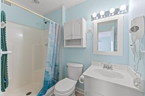 Un bagno con doccia, WC, lavandino e asciugacapelli.
