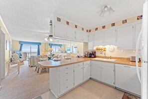 A spacious kitchen with white cabinets, a central island, and a dining area with chairs and a table.
