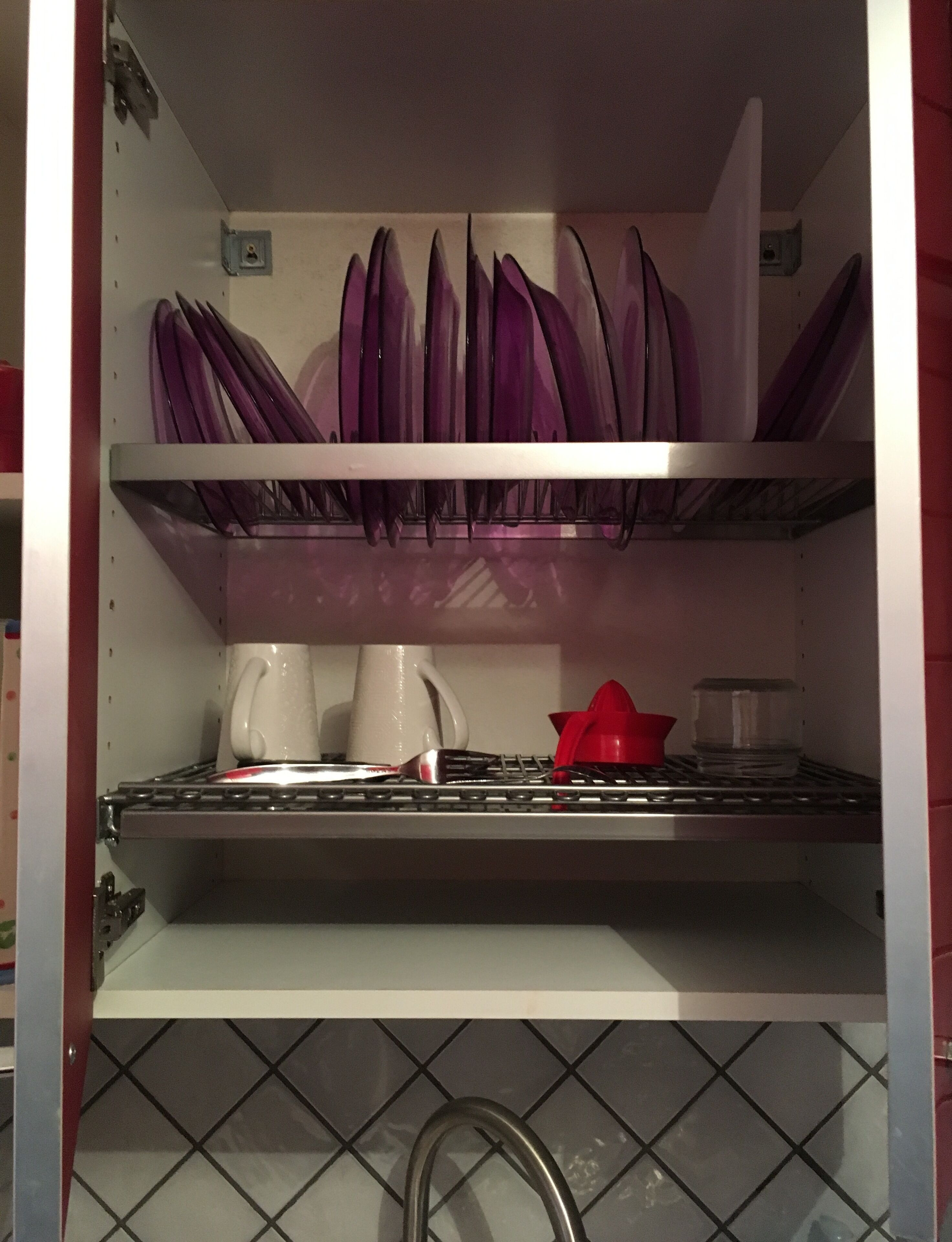 Una cucina con scolapiatti, una macchina da caffè e un contenitore rosso sul piano di lavoro.