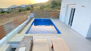 Ein Pool auf dem Dach mit Liegestühlen und einer Steinsäule.