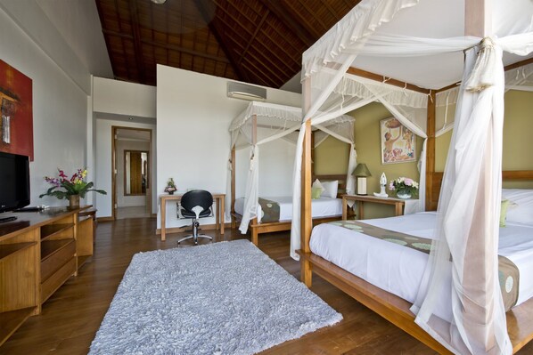 A bedroom with a canopy bed, a desk with a chair, and a television.