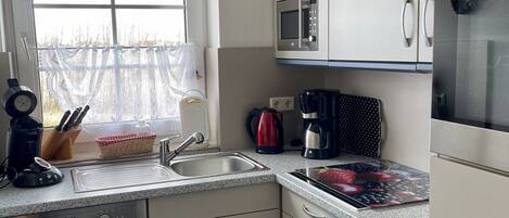 Una cocina moderna con ventana, electrodomésticos de acero inoxidable y lavavajillas.