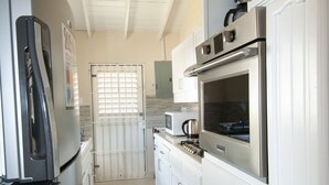 A kitchen with white cabinets, a stainless steel refrigerator, and a microwave. - Cozy 2-Bedrooms across from West Coast beach (St James)