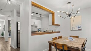 Una cocina moderna con armarios blancos, encimera de madera y una lámpara colgante.