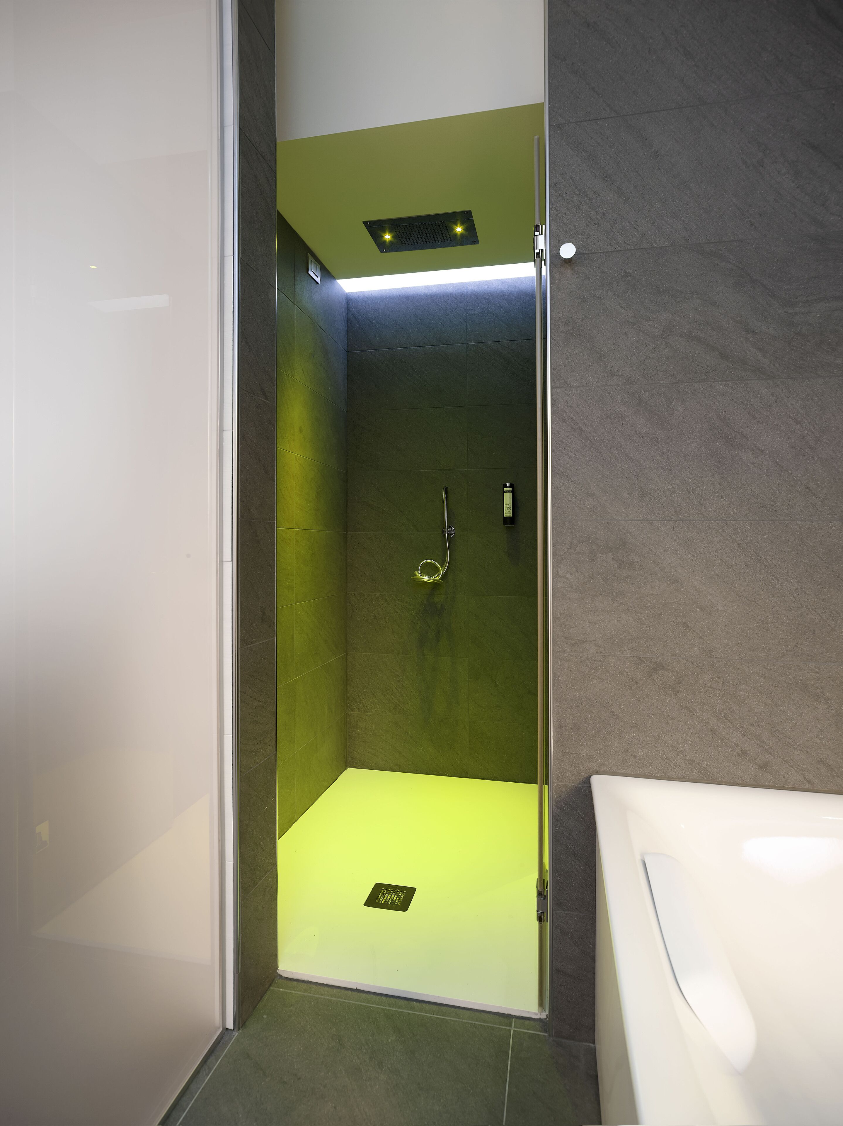 A modern shower with a glass door, a visible showerhead, and a control panel on the wall.