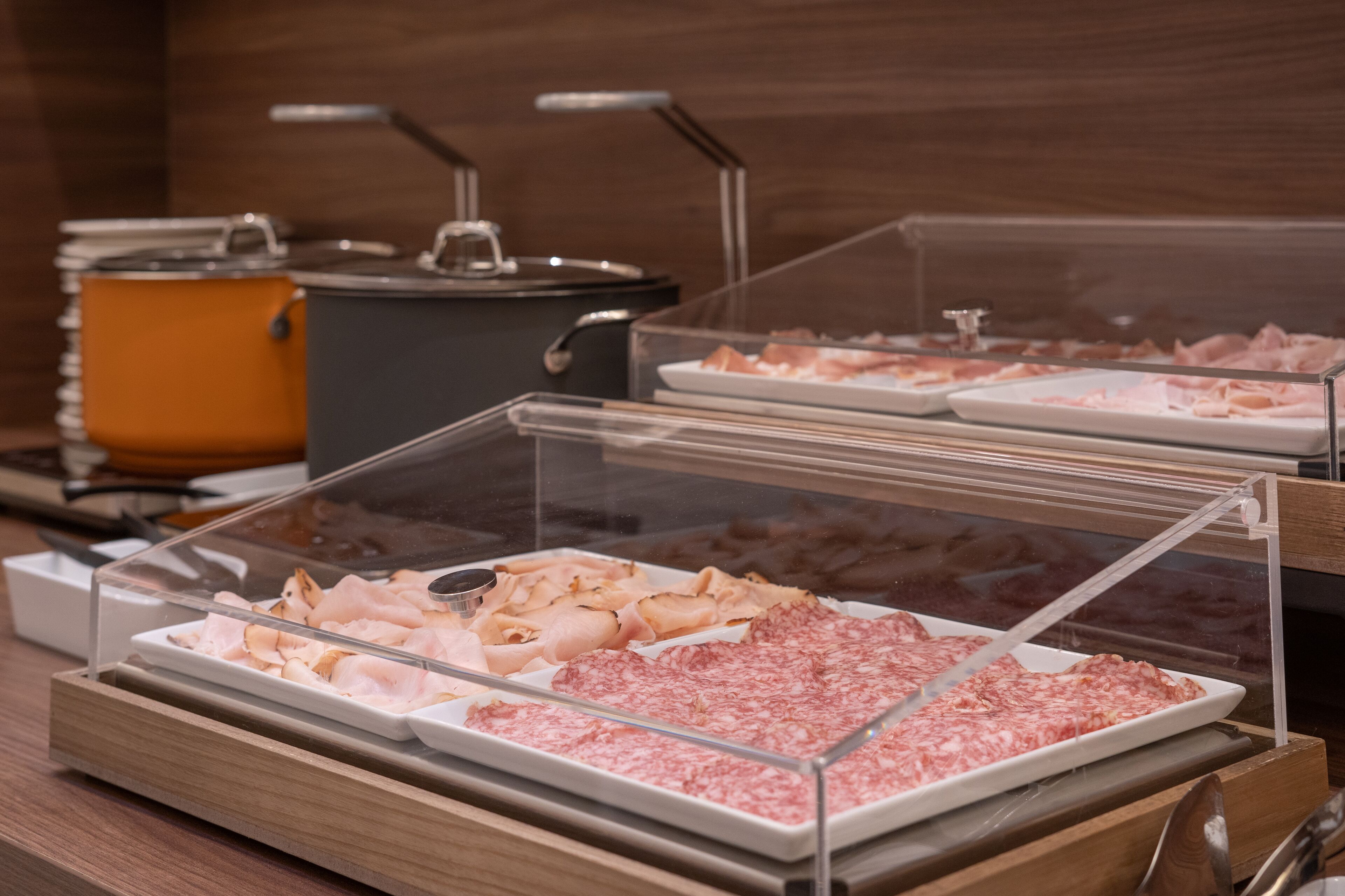 A buffet with various meats and a pot in the background.