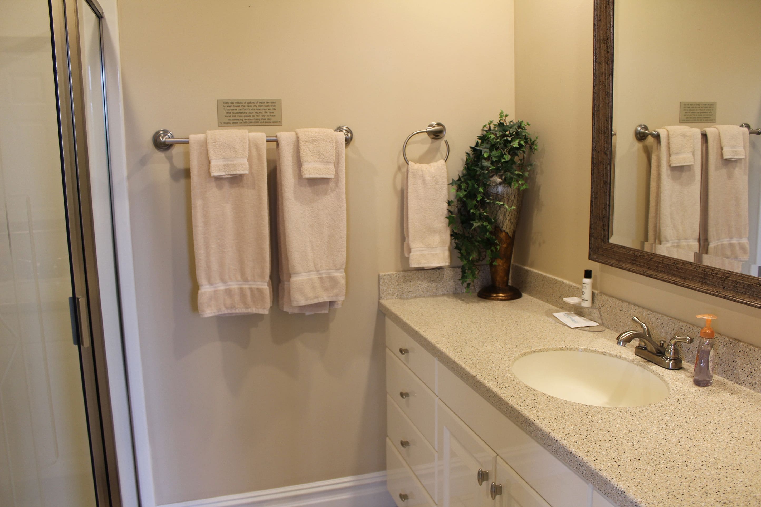 A bathroom with a sink, mirror, towel rack, and a potted plant.