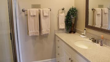 A bathroom with a sink, mirror, towel rack, and a potted plant.