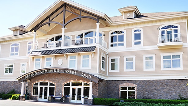 A multi-story hotel with a prominent entrance, balconies, and a stone facade. - Riverwalk Place Resort & Spa (Gladwin)