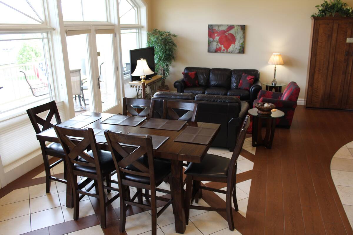 A dining area with a table and chairs, a sofa, and a television.