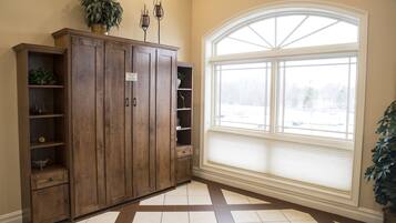 Une pièce avec une grande armoire en bois, une fenêtre avec des stores et un sol carrelé.