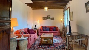 Ein gemütliches Wohnzimmer mit Holzbalkendecke, zwei Sofas, einem Couchtisch und einem Teppich.