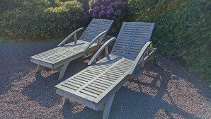 Zwei Holz-Loungesessel mit Metallgestellen auf einem Kiesuntergrund.