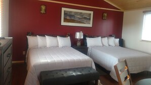 Una habitación con dos camas, un banco de madera, un aparador y un cuadro en la pared.