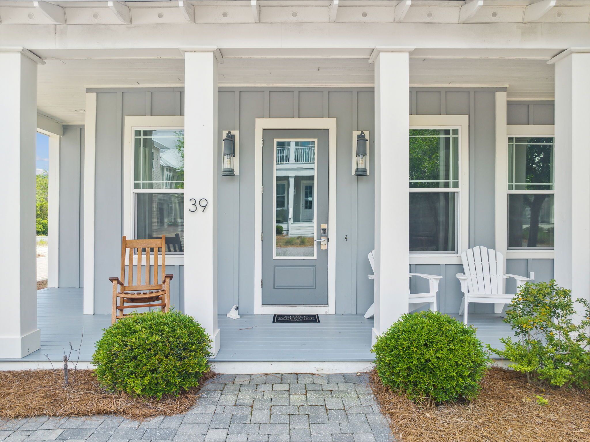A house with a grey front door, two white chairs, and a number '39' on the wall.