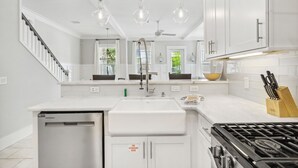 A modern kitchen with white cabinetry, a stainless steel dishwasher, a gas stove, and pendant lighting. - Prime Location Near Community Pool | 6 Beach Bikes | Tram to Easy Beach Access (Santa Rosa Beach)